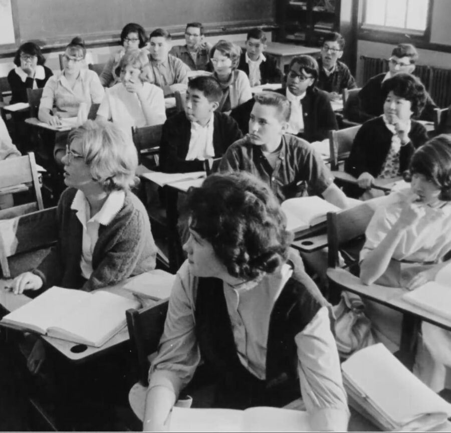 Students seated at desks in rows in a mid-20th-century classroom
